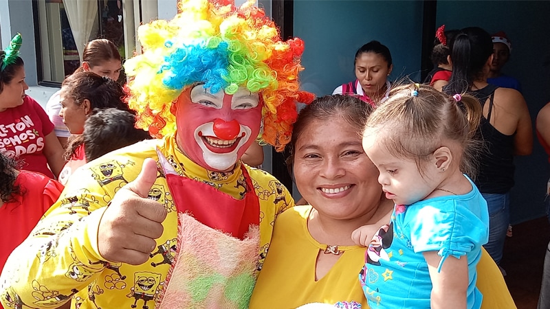 Payaso Jin Kerosín, junto a una madre de familia que carga a su hijo en sus brazos. 