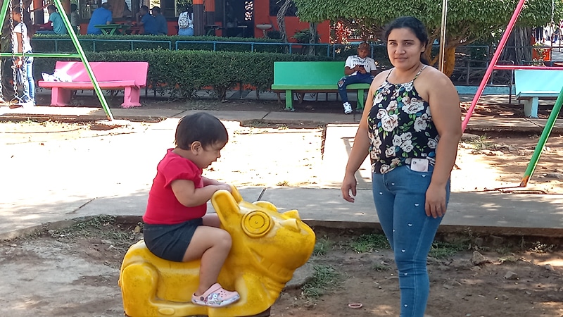 Una madre observa a su hija que disfruta de los juegos del parque de Juigalpa. 