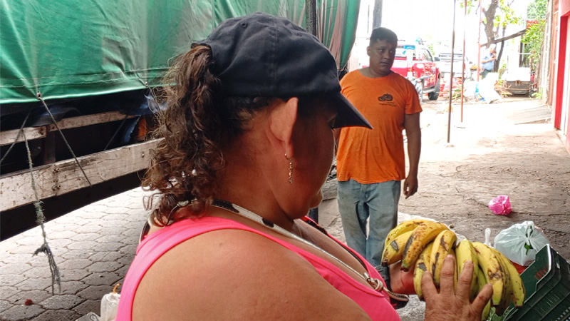 Mujer compra los bananos para incluirlo en el paquete de su purísima. 