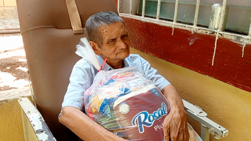 Una de las personas de la tercera edad, con su paquete alimenticio. 